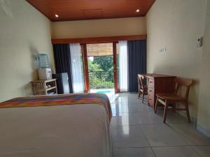 sypialnia z łóżkiem, biurkiem i oknem w obiekcie Meme Lan Bape Guest House w mieście Ubud