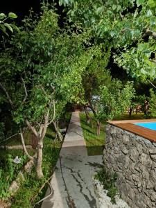 a garden with a stone wall and a swimming pool at ТИФАНИ -1 этаж дома с бассейном in Bjni +15 photos