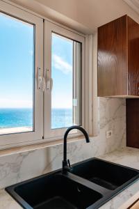 a kitchen with a sink and two windows at Kristianna Apartments in Dhërmi
