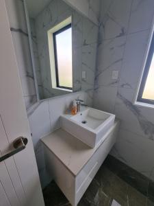 a white bathroom with a sink and a mirror at BEHOME - Modern Guest Suite in Kumeu +5 photos