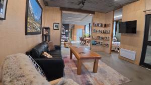 a living room with a black leather couch and a table at Blue Mountains Loft, Tapanui in Glenkenich