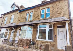 a brick house with a white door and windows at Peak District Cottage in Buxton