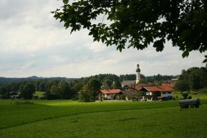 un campo verde con una iglesia a lo lejos en Camperstellplätze, en Fischbachau