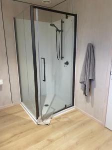 a shower with a glass door in a bathroom at Point Wells Holiday Apartment in Big Omaha