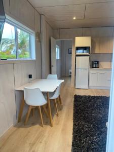 a kitchen and dining room with a white table and chairs at Point Wells Holiday Apartment in Big Omaha