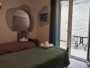 a bedroom with a bed and a door to a balcony at Niki Rooms in Tinos