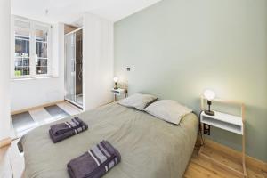 Un dormitorio con una cama grande con dos toallas encima. en Chic T2 rénové au cœur de Clermont-Ferrand à 2 min de Jaude !, en Clermont-Ferrand