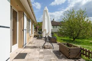 a patio with an umbrella and a table at La Maison et son jardin sur le Canal de Bourgogne in Ravières