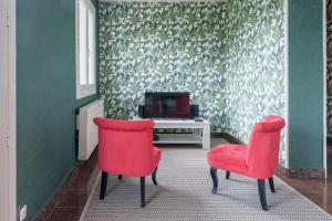 a room with two red chairs and a television at La Maison et son jardin sur le Canal de Bourgogne in Ravières