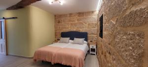 a bedroom with a bed and a stone wall at Palleira da Meiroá in Esgos