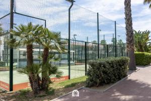 a tennis court with palm trees and a fence at Mediterranean Way - Punta Prima 17 in La Pineda