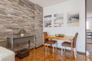una sala da pranzo con tavolo e sedie e un muro di mattoni di Casa Magó a Espinho
