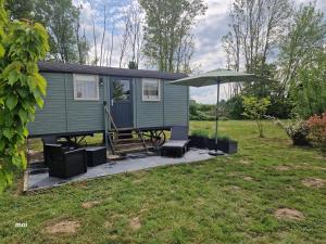 a green tiny house with a table and an umbrella at Les trois bergers in Serley
