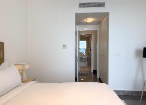 Un dormitorio con una cama blanca y un pasillo. en AmazINN Places Incredible views YOO Building, en Panamá