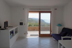 a living room with a couch and a sliding glass door at Roccette OndaTURCHESE, Vista Mare e Jacuzzi Privata in Costa Paradiso