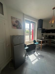 a kitchen with a refrigerator and a table and a window at Chez Léa-Magnifique maison au centre-ville in Chaumont