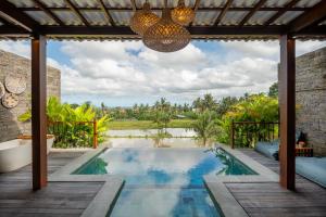 an outdoor pool with a chandelier and a house at Emana Akatara in Ubud