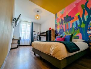 a bedroom with a large bed with a colorful wall at Hôtel Des Arts, Artisanal et Indépendant in Montpellier