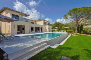 Un patio trasero con piscina y una casa. en Villa Celina - Sea view, en Beauvallon