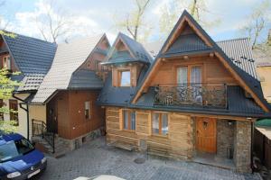 une maison en bois avec un toit et un balcon dans l'établissement Góralski Domek Waluś Zakopane - ŚCISŁE CENTRUM - Jedyny domek na Krupówkach, à Zakopane