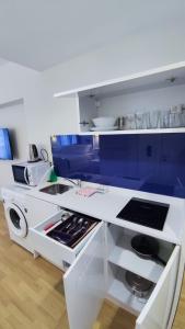 een keuken met witte toonbanken en blauwe kasten bij Orbi City 61 in Batoemi
