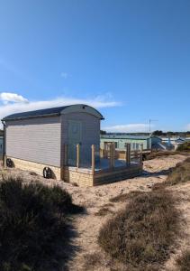 a small shack on a beach with the ocean in the background at Shephards Hut by the Beach in Findhorn +5 photos