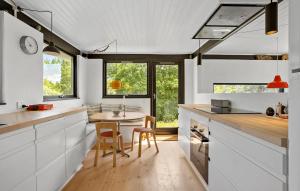 Una cocina con gabinetes blancos y una mesa y sillas. en Awesome Home In Knebel, en Ørby
