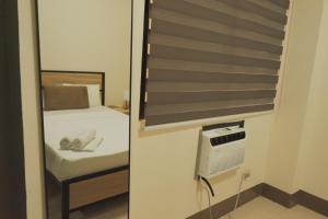 a small room with a bed and a mirror at Brightwood Hotel & Residences in Manila