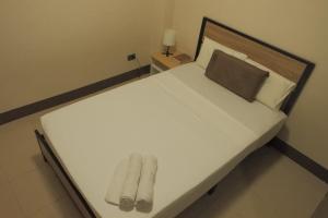 a white bed with two pairs of slippers on it at Brightwood Hotel & Residences in Manila +40 photos