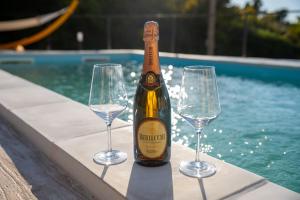 a bottle of champagne and three wine glasses next to a swimming pool at Villa Grace with private pool in Ascea