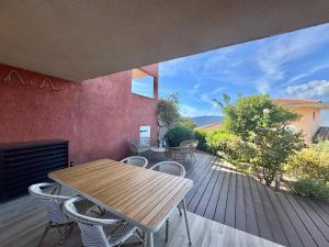 a wooden deck with a table and chairs on it at Deux pièces tout confort sur les hauteurs de Propriano in Propriano