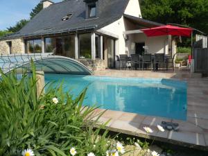 a swimming pool in front of a house with an umbrella at Thy lou in Baden