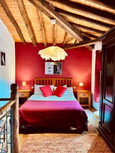 a bedroom with red walls and a bed with red pillows at Salto del Caballo in La Fontañera