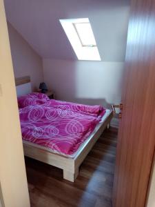 a bedroom with a bed with pink sheets and a skylight at Apartmán Nicolass in Šakvice