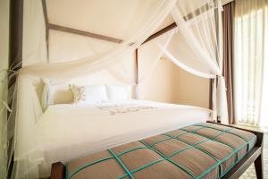 a bedroom with a white bed with curtains and a window at Coco Luxury Villa Mũi Né in Ấp Thiện Phước +17 photos
