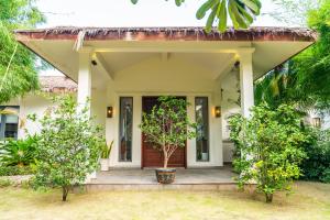 a small house with a porch and trees at Coco Luxury Villa Mũi Né in Ấp Thiện Phước