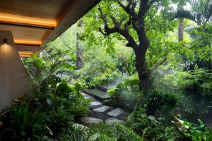 a garden with a tree and a walkway at The Kemilau Ubud in Ubud