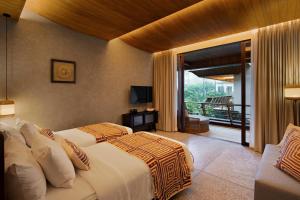a bedroom with two beds and a balcony at The Kemilau Ubud in Ubud