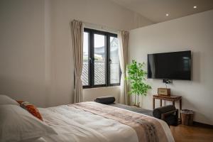 a bedroom with a bed and a flat screen tv at Riverside Inn HANGZHOU in Hangzhou