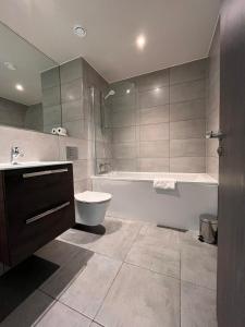 a bathroom with a tub and a toilet and a sink at Cosy Studio with private entrance & Parking in Bracknell
