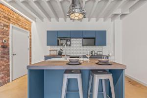 une cuisine avec des placards bleus et un comptoir avec des tabourets dans l'établissement Iron Haven - Central B'ham - Luxury Apt, à Birmingham 27 autres photos