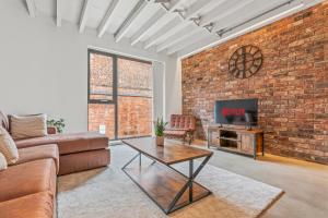 un salon avec un canapé et une télévision dans un mur de briques dans l'établissement Iron Haven - Central B'ham - Luxury Apt, à Birmingham