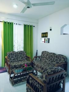 a living room with two couches and green curtains at Delight Villa in Tangalle