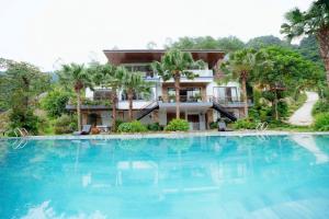 a large swimming pool in front of a house at Sunset Haven Villa - Venuestay in Sóc Sơn