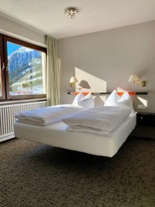 a bedroom with a large bed with a large window at Arlberg Motel Ski-In & Ski-Out access to Austrias largest ski area in Stuben am Arlberg +26 photos