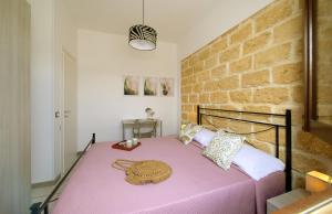 een slaapkamer met een roze bed met een bakstenen muur bij Villa Lilibeth in San Vito lo Capo