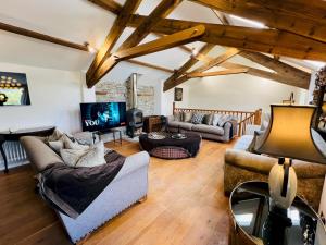 ein Wohnzimmer mit Sofas und Fernseher in der Unterkunft Pass the Keys Stunning 3-Bed Cottage Shepherd Hut Peak Views in Castleton