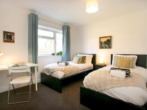 a bedroom with two beds and a desk and a window at Pass the Keys Bright & Cosy Home with Garden Free Parking in Nottingham