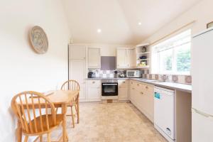 a kitchen with white cabinets and a table and chairs at Buckingham Cottage - Lancombes House in Powerstock