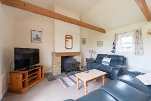 a living room with a couch and a fireplace at Buckingham Cottage - Lancombes House in Powerstock +3 photos